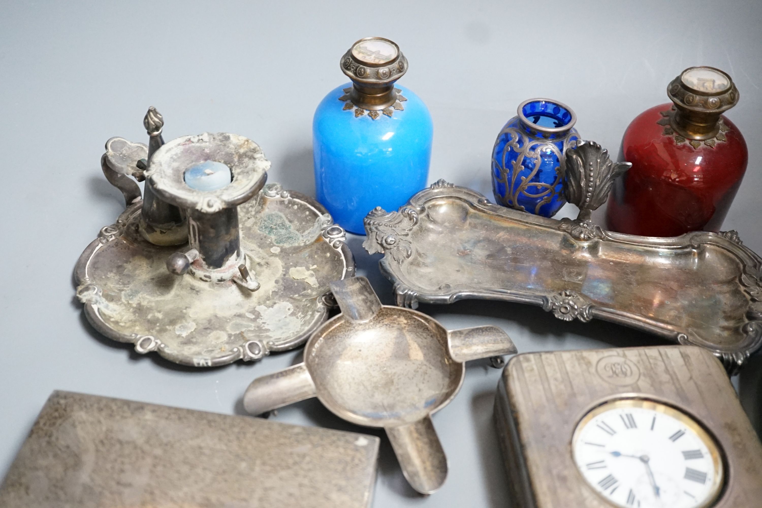 An Edwardian silver mounted travelling pocket watch case with 8-day pocket watch, one other travelling pocket watch in case, a silver mounted cigarette box, a silver ashtray, a plated snuffers stand and plated chambersti